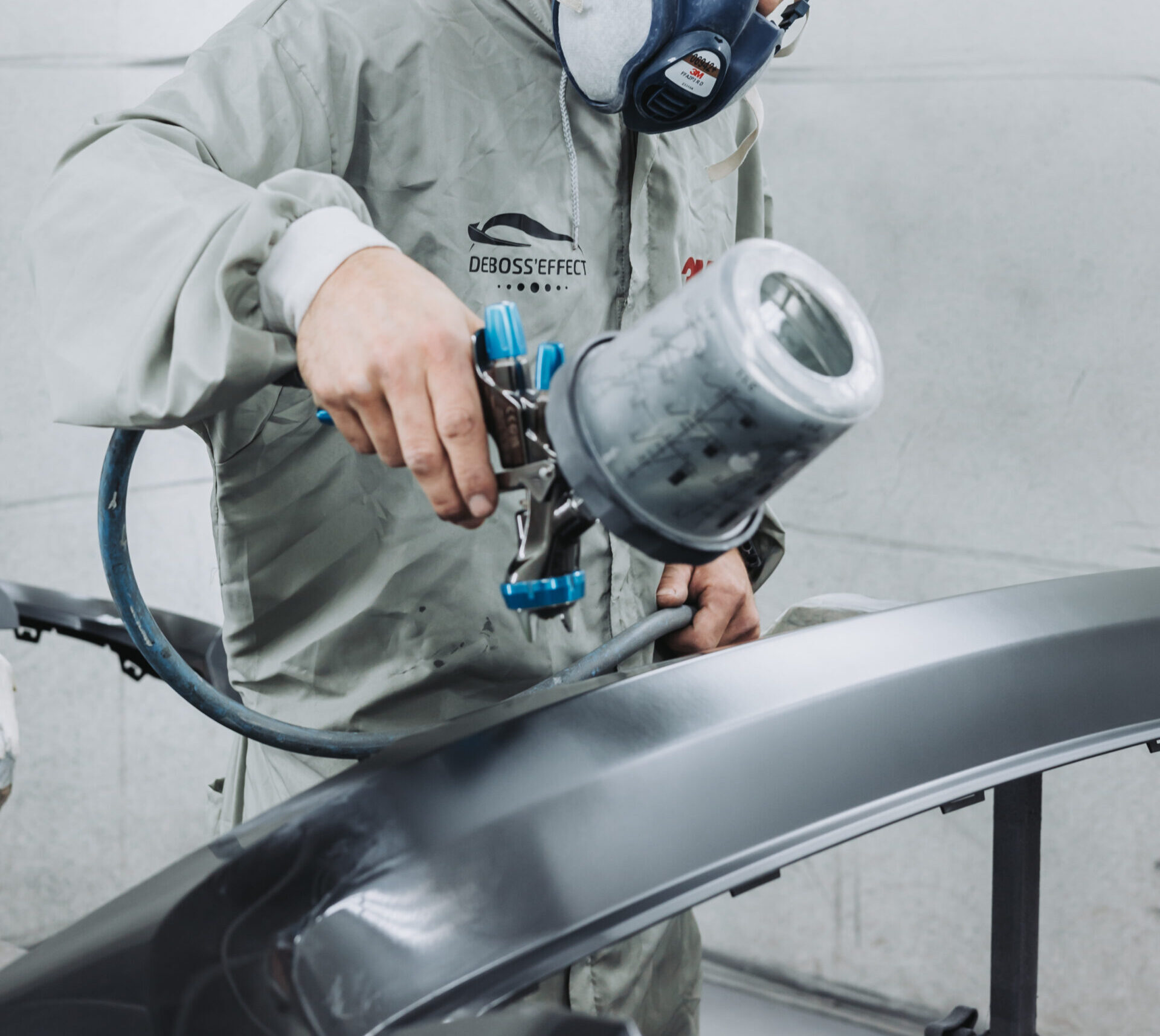 Technicien de la Carrosserie DEVINAST appliquant de la peinture sur un véhicule à Brognard